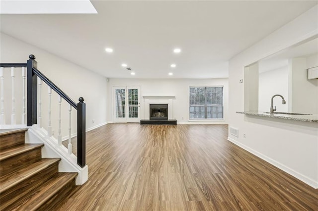 unfurnished living room featuring sink and hardwood / wood-style floors