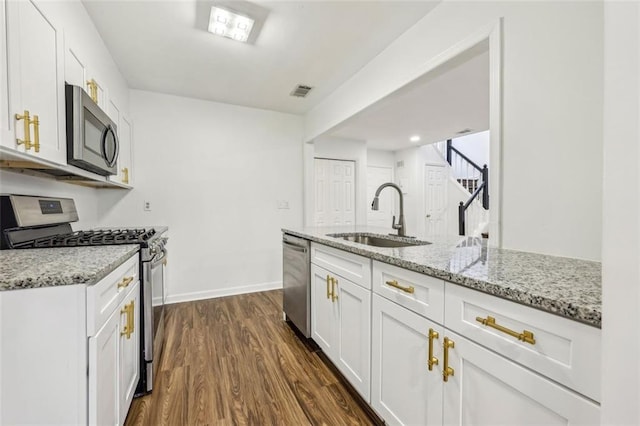 kitchen featuring white cabinetry, sink, stainless steel appliances, light stone countertops, and dark wood-type flooring