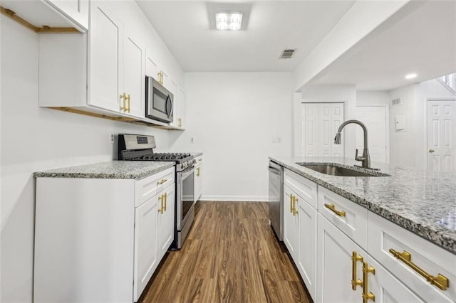 kitchen with appliances with stainless steel finishes, light stone countertops, sink, and white cabinets