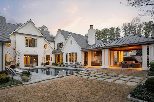 back house at dusk with a gazebo, outdoor lounge area, and a patio