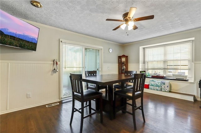 dining space with plenty of natural light, a wainscoted wall, and dark wood finished floors