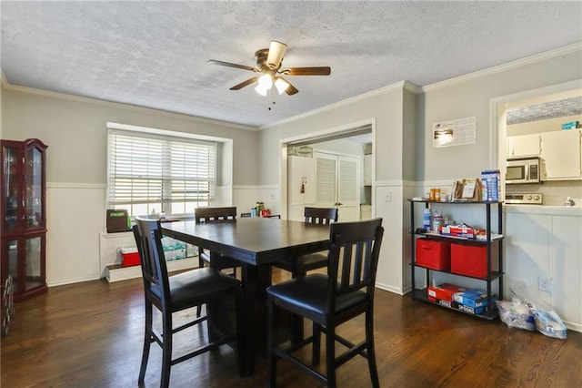 dining room with dark wood-style floors, ornamental molding, wainscoting, ceiling fan, and a textured ceiling