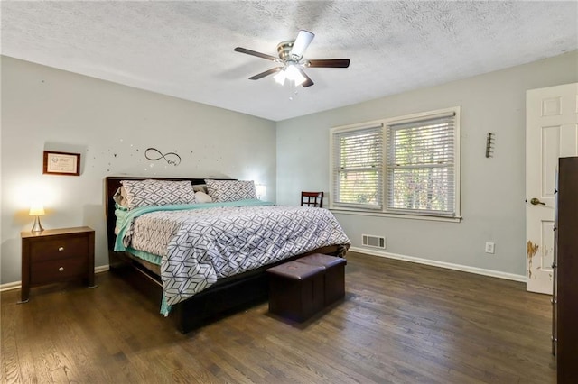 bedroom with a textured ceiling, dark wood finished floors, visible vents, and baseboards