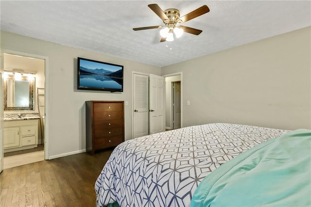 bedroom featuring a textured ceiling, baseboards, a closet, dark wood-style floors, and ensuite bath