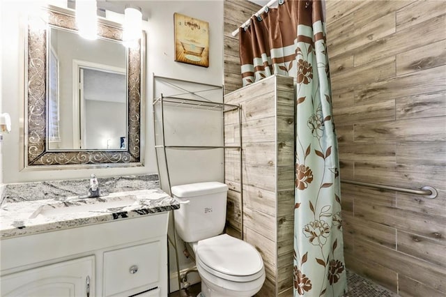 full bathroom featuring tiled shower, vanity, and toilet