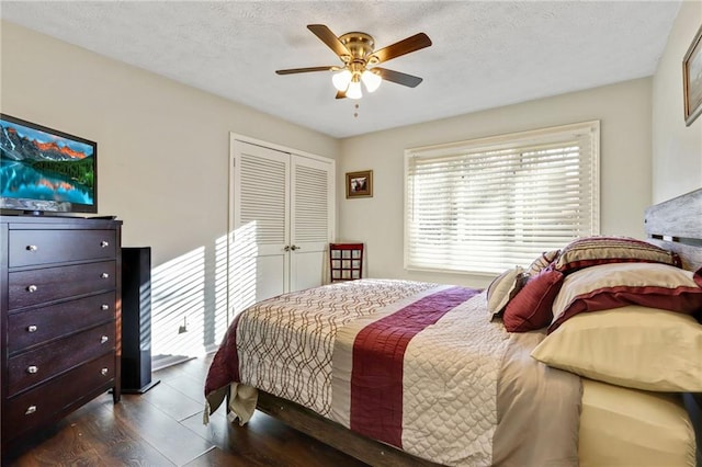 bedroom with ceiling fan, a textured ceiling, dark wood finished floors, and a closet