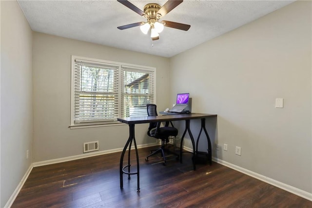 home office with a ceiling fan, dark wood finished floors, visible vents, and baseboards