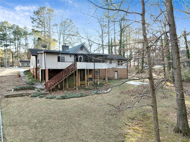 back of house with a sunroom, a chimney, stairway, a deck, and brick siding