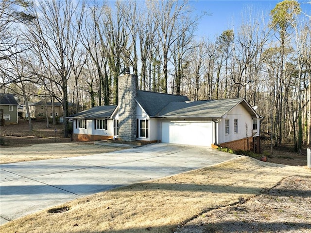 view of front facade with a garage, a chimney, concrete driveway, and brick siding