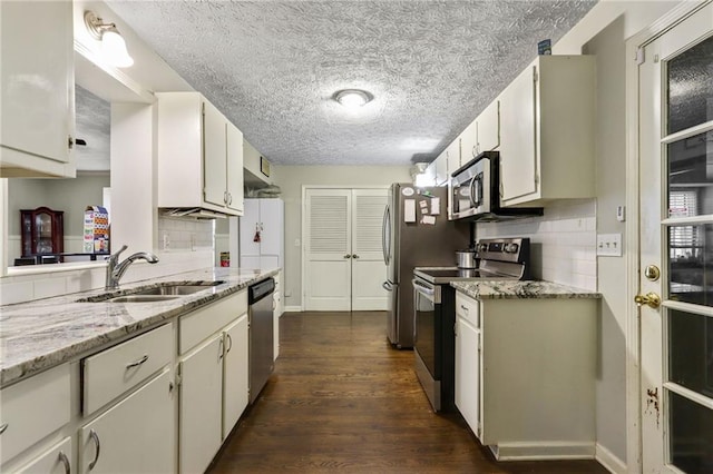 kitchen featuring tasteful backsplash, light stone counters, dark wood-style flooring, stainless steel appliances, and white cabinetry