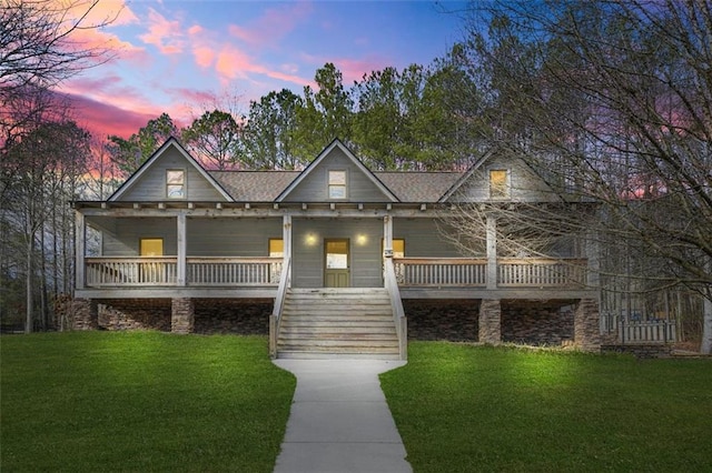 view of front of home with a porch, a lawn, stairway, and a shingled roof