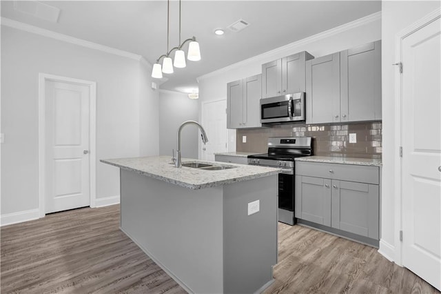 kitchen with decorative light fixtures, an island with sink, sink, gray cabinetry, and stainless steel appliances