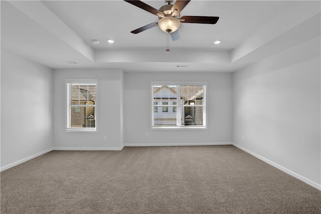 carpeted empty room with ceiling fan and a tray ceiling