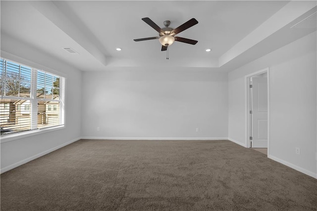 carpeted empty room featuring ceiling fan and a raised ceiling