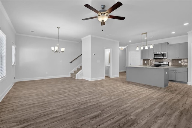 unfurnished living room with hardwood / wood-style flooring, crown molding, sink, and ceiling fan with notable chandelier