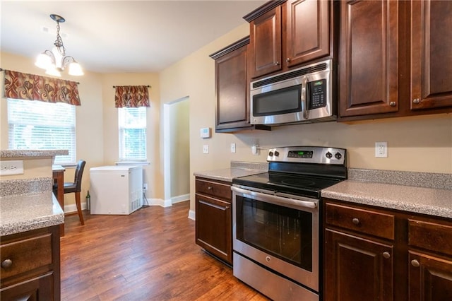 12275 Styron Dr, Hampton, GA 30228 - kitchen featuring appliances with stainless steel finishes, dark brown cabinetry, dark wood-style flooring, light countertops, and a chandelier