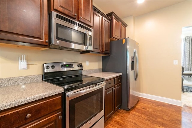 12275 Styron Dr, Hampton, GA 30228 - kitchen featuring stainless steel appliances, light wood-style floors, baseboards, and dark brown cabinets