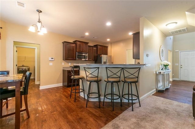12275 Styron Dr, Hampton, GA 30228 - kitchen featuring appliances with stainless steel finishes, a chandelier, a breakfast bar area, dark wood-type flooring, and a peninsula