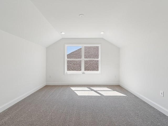 additional living space with baseboards and vaulted ceiling