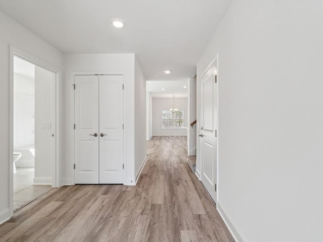 hallway featuring a chandelier, recessed lighting, light wood-style flooring, and baseboards