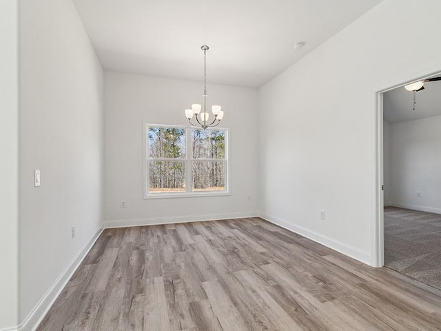 empty room featuring baseboards, a notable chandelier, and wood finished floors