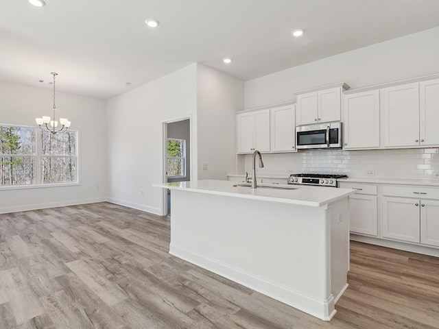 kitchen with a sink, stainless steel microwave, backsplash, light countertops, and stove