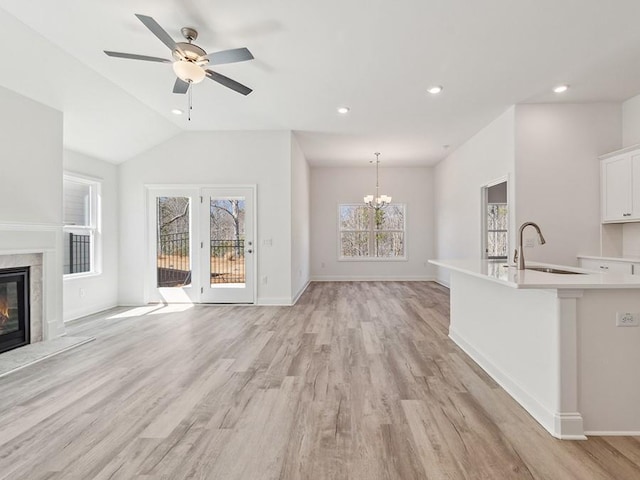 unfurnished living room featuring a premium fireplace, baseboards, light wood-type flooring, and a sink