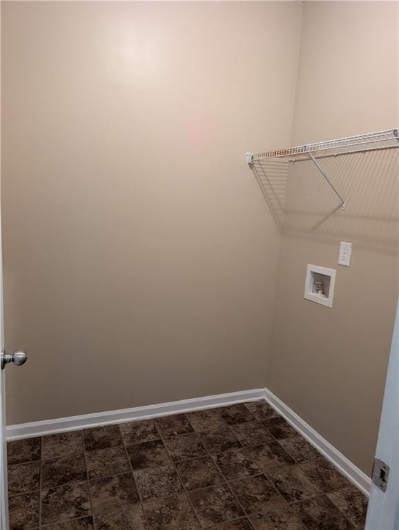 washroom with hookup for a washing machine, baseboards, and stone finish flooring