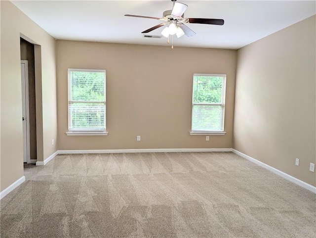 spare room featuring healthy amount of natural light, carpet flooring, ceiling fan, and baseboards