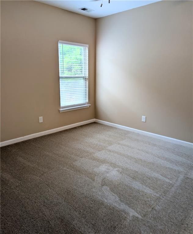 carpeted spare room featuring baseboards
