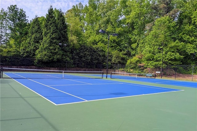 view of tennis court featuring fence and community basketball court