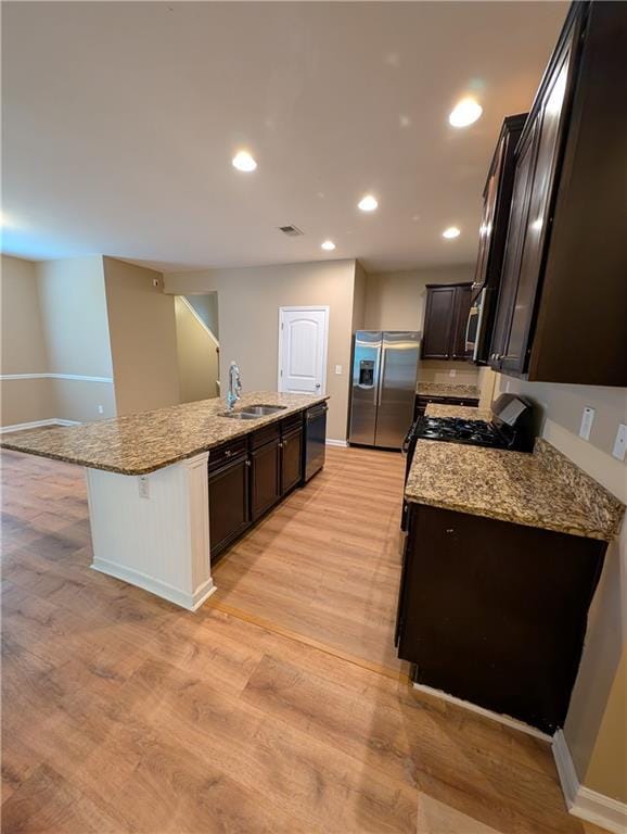kitchen featuring stainless steel refrigerator with ice dispenser, range with gas stovetop, a sink, dishwasher, and baseboards