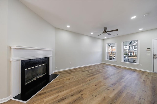 unfurnished living room featuring baseboards, ceiling fan, a premium fireplace, wood finished floors, and recessed lighting