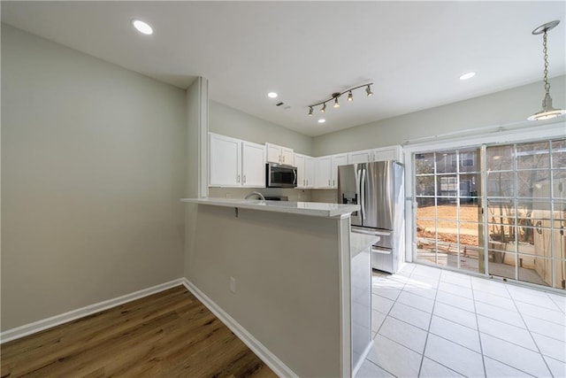 kitchen featuring baseboards, white cabinets, a peninsula, stainless steel appliances, and light countertops