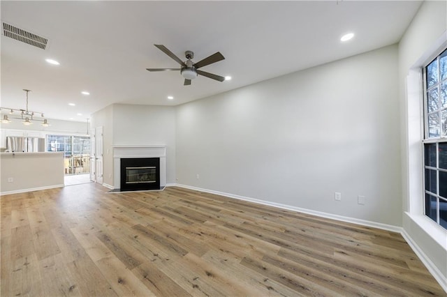 unfurnished living room featuring a fireplace with flush hearth, visible vents, light wood-style flooring, and recessed lighting