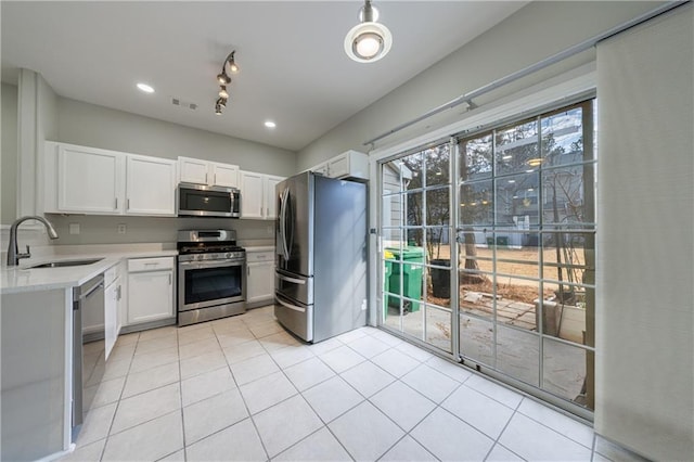 kitchen featuring light tile patterned floors, appliances with stainless steel finishes, white cabinets, and a sink