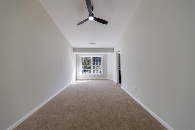 carpeted spare room featuring visible vents, ceiling fan, and baseboards