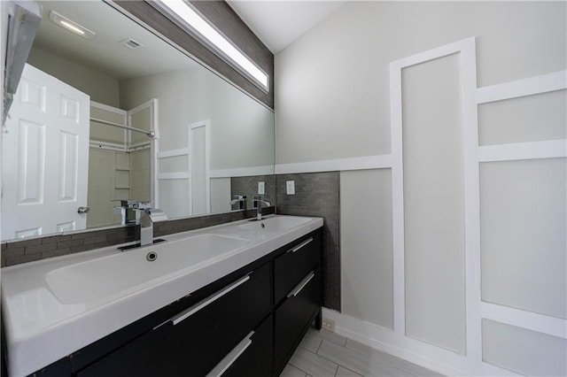 bathroom with wainscoting, visible vents, a sink, and double vanity