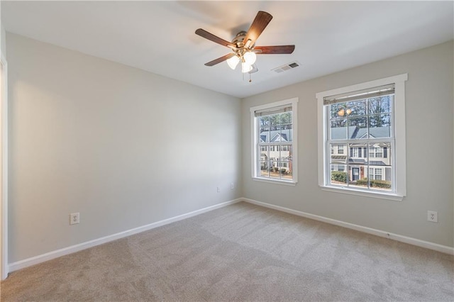 unfurnished room featuring light carpet, a ceiling fan, visible vents, and baseboards