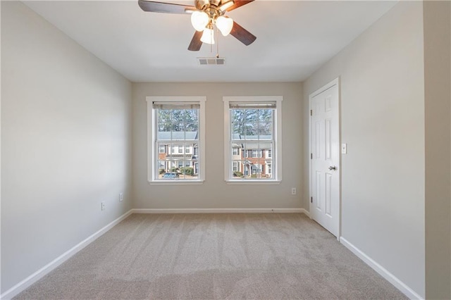 carpeted empty room featuring ceiling fan, visible vents, and baseboards