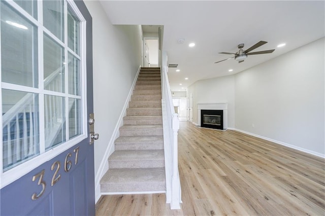 stairway featuring a glass covered fireplace, visible vents, recessed lighting, and wood finished floors