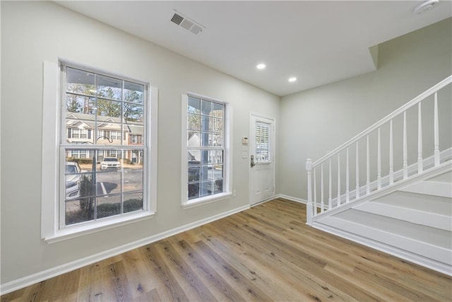 foyer entrance with a healthy amount of sunlight, visible vents, stairway, and wood finished floors