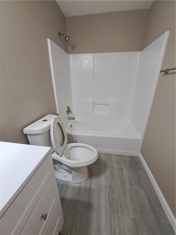 bathroom featuring bathing tub / shower combination, vanity, toilet, and wood finished floors