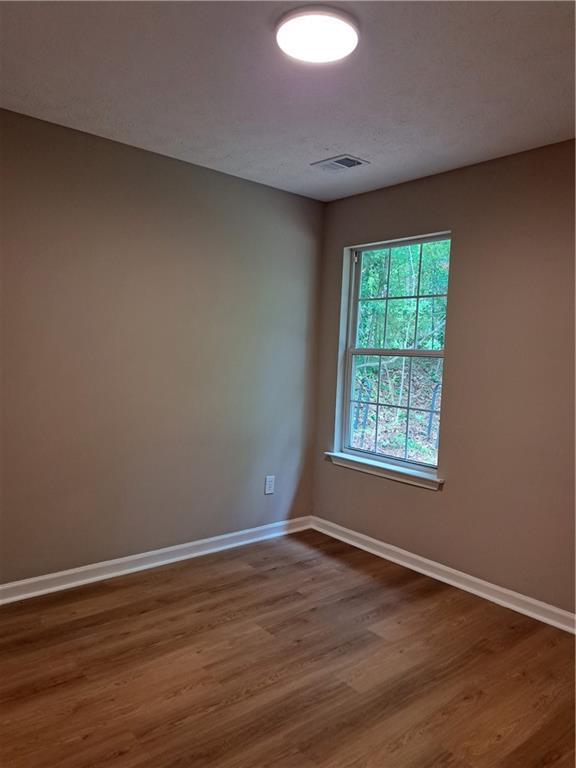spare room with baseboards, dark wood finished floors, and visible vents