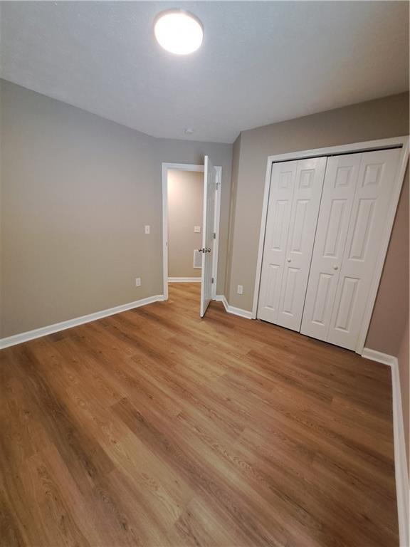 unfurnished bedroom with light wood-type flooring, baseboards, and a closet