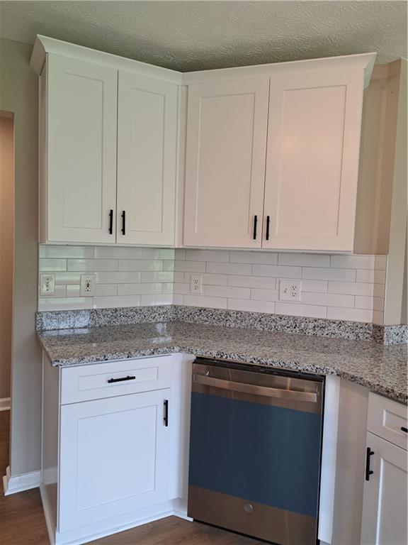 kitchen featuring light stone counters, backsplash, dark wood finished floors, and dishwasher