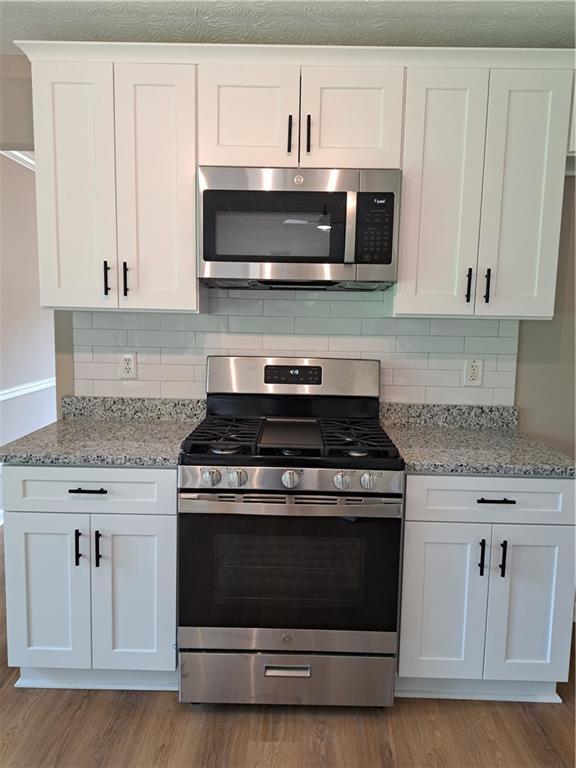 kitchen featuring white cabinets, stainless steel appliances, and light wood-style flooring