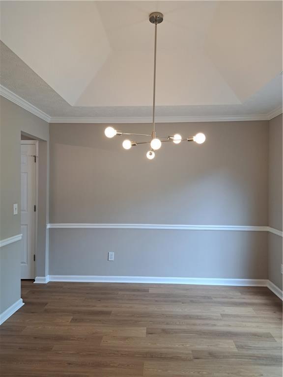 unfurnished room with ornamental molding, lofted ceiling, and wood finished floors