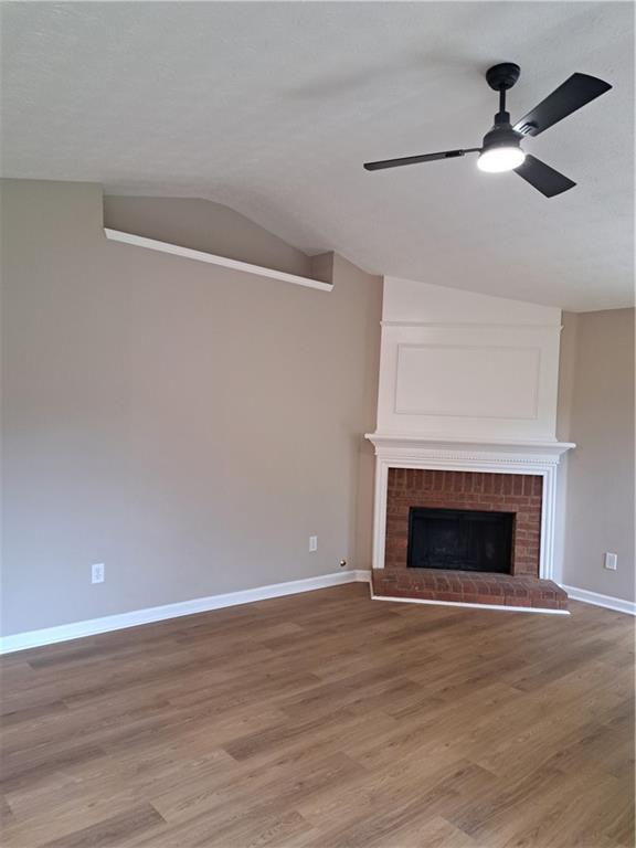 unfurnished living room featuring light wood-style floors, baseboards, ceiling fan, and vaulted ceiling