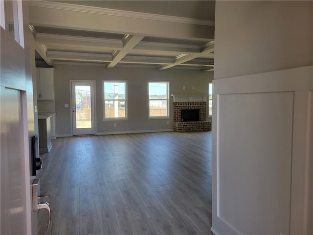 unfurnished living room featuring beamed ceiling, wood-type flooring, ornamental molding, coffered ceiling, and a brick fireplace